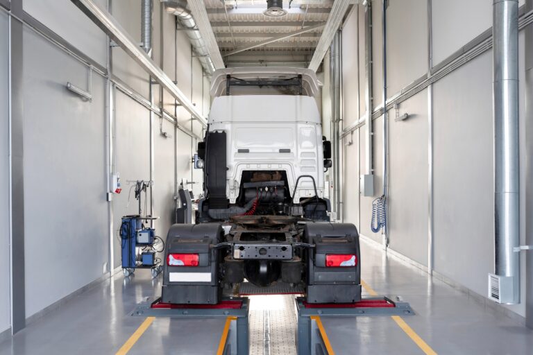 LKW in moderner Werkstatt- oder Prüfhalle auf einer Fahrzeughebebühne für Inspektion oder Gutachten bzw. Begutachtung.