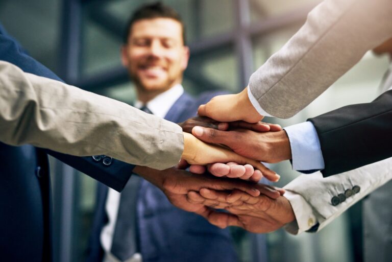 Mehrere Personen in Businesskleidung legen ihre Hände übereinander – Teamwork/Unterstützung für Verkehrsrecht.